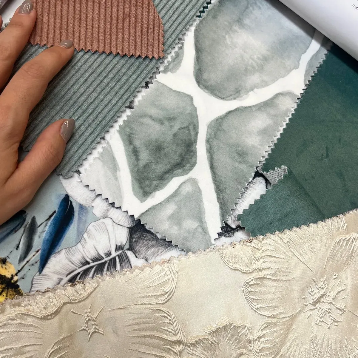 Muestrario de telas y texturas en tonos verdes y crema sostenido en la mano